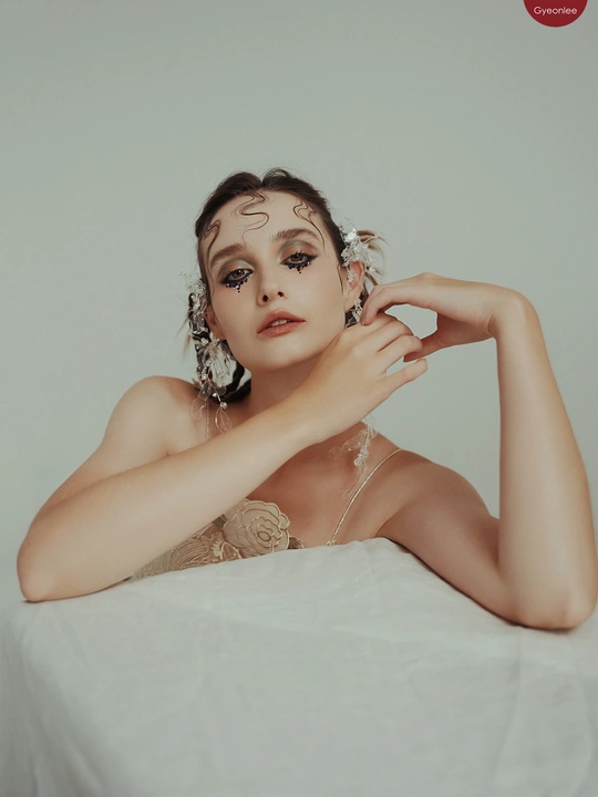 一个年轻女子坐在桌子前 脸上盖着白布 双手抚摸着头发。