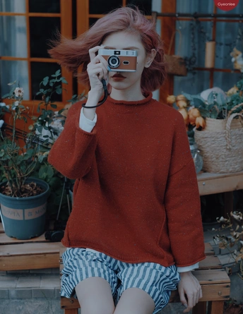 一位红发女青年坐在长凳上 用相机拍照。