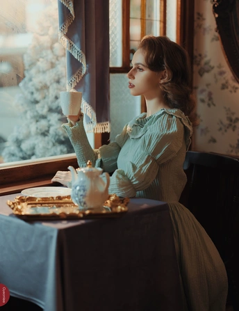 一位穿着连衣裙的女士坐在桌子旁喝一杯茶
