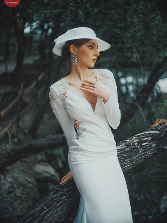 一位穿着白色连衣裙和帽子的女人在森林中与倒下的树木合影。