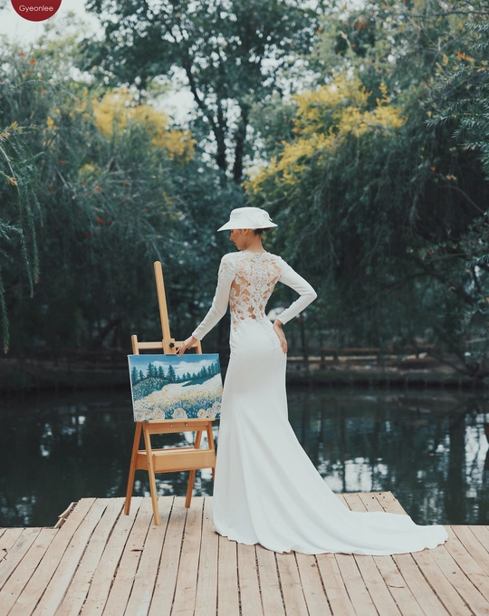 一位穿着白色连衣裙和帽子 手持新娘照片的女性