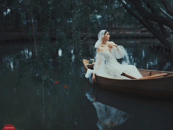 一位穿着婚纱的女士在湖上划船的照片