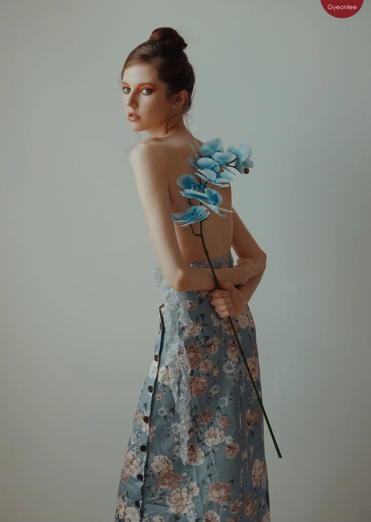 一位穿着连衣裙的年轻女子 holding blue flowers