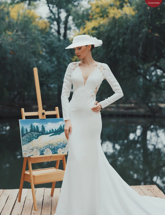 一位穿着白色连衣裙和帽子的女士正在为拍照摆姿势。