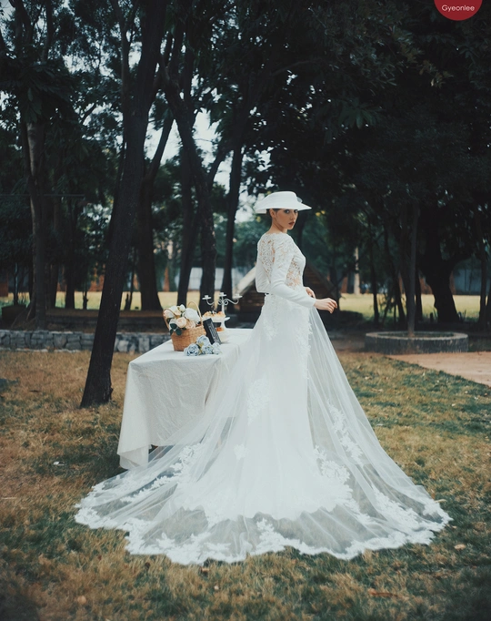 一位穿着白色连衣裙和帽子站在桌子旁边的女士