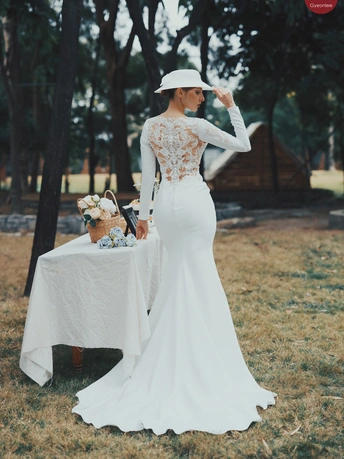 一位穿着白色婚纱 拖尾 戴着帽子的女人站在桌子外面