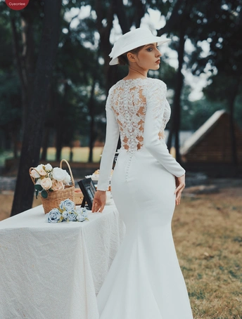 一位穿着白色连衣裙和帽子站在桌子旁边的女士