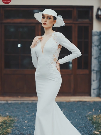 一位穿着来自Person品牌白色连衣裙的模特 配有拖尾和帽子。