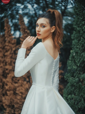 一位美丽的年轻女士穿着一件白色婚纱站在户外环境中 穿着一件白色连衣裙 摆出姿势。