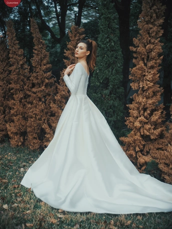 一位穿着白色连衣裙 拖尾站在森林中的女人 穿着新婚礼服 摆姿势