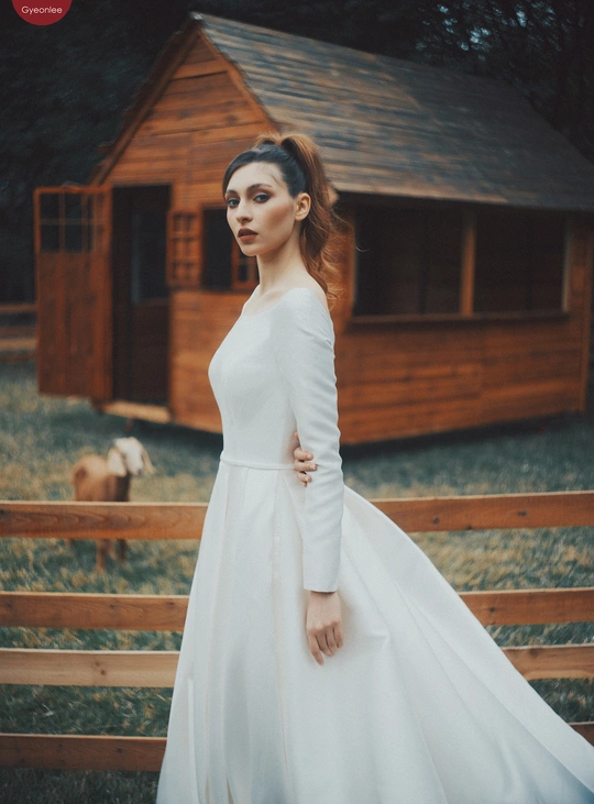 一位穿着白色婚纱站在木质围栏前的女性 摆出模特姿势为白色婚纱拍摄