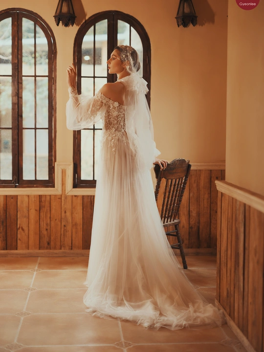 新娘穿着婚纱和头纱站在窗户前