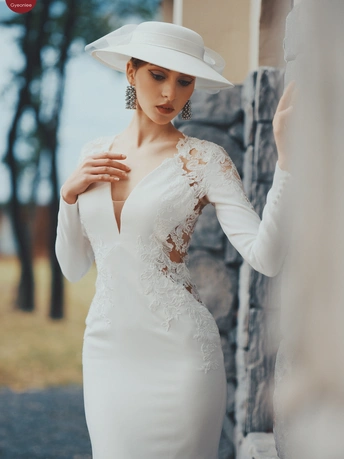 一位穿着白色婚纱和帽子的模特在户外摆姿势