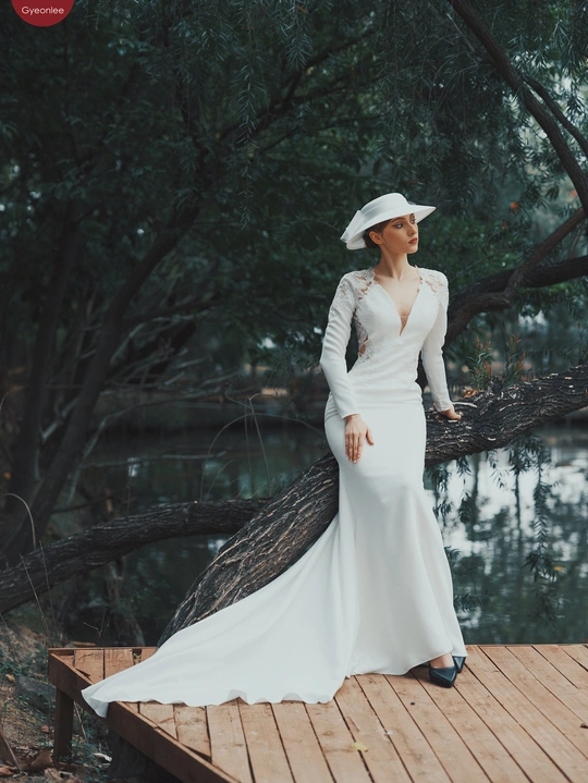 一位穿着白色连衣裙和帽子站在一棵树旁的美丽女士