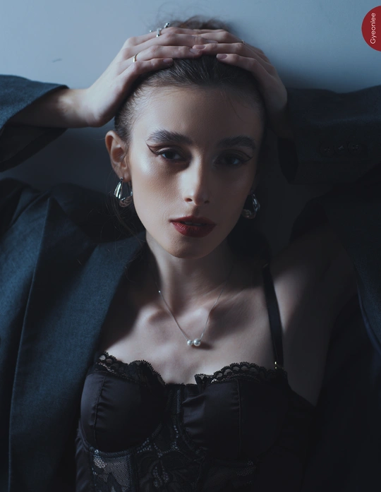 一位年轻女子穿着黑色站在一面墙前为肖像拍照