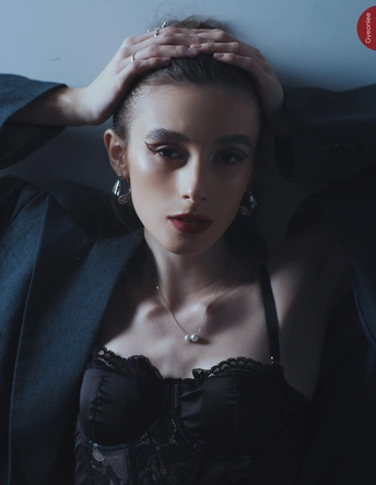 一位年轻女子穿着黑色站在一面墙前为肖像拍照