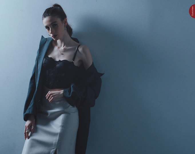 一位穿着黑色外套的模特站在蓝色墙壁前