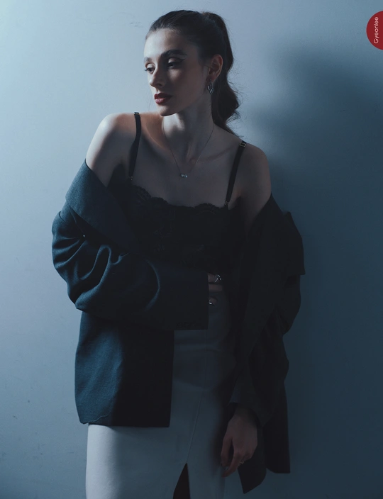 一位年轻女子站在蓝色墙壁前 双臂交叉在肩膀上