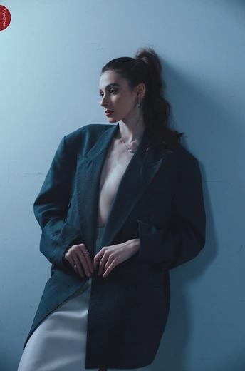 一位穿着蓝色外套的女性站在蓝色墙壁前