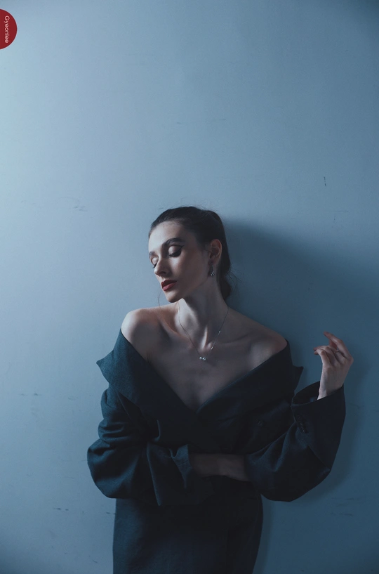 一位穿着黑色衣服的年轻女子在蓝色墙壁前摆姿势