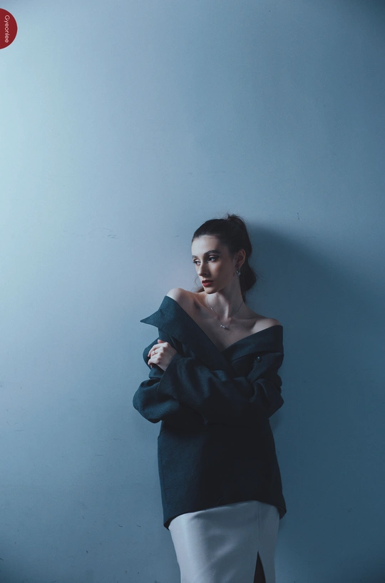 一位穿着黑白衣服的年轻女子靠在蓝色墙壁前摆姿势