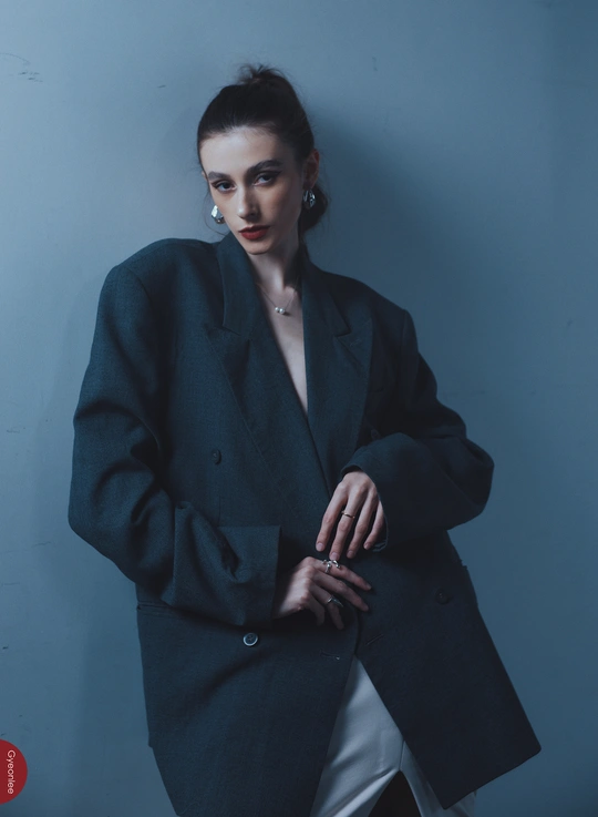 一位穿着黑色外套的美丽女士站在蓝色的墙上