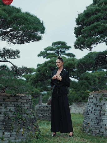 一位穿着黑色连衣裙的女人站在一把红色雨伞旁边