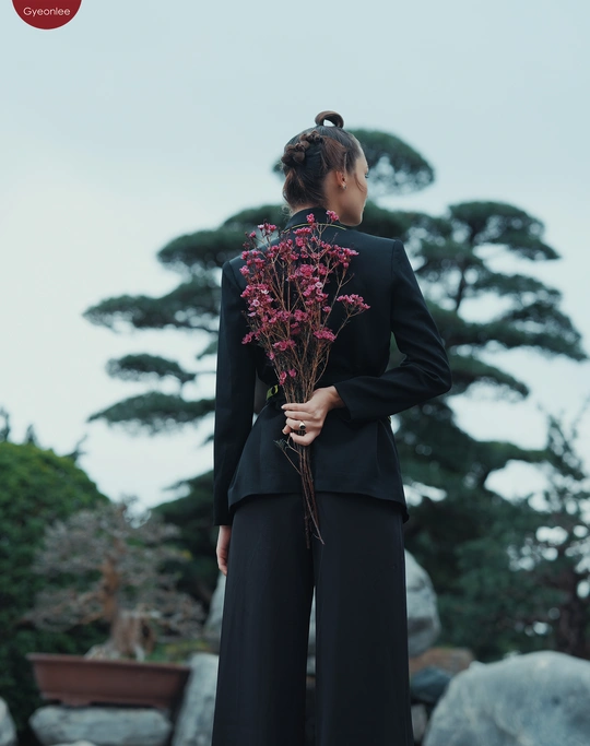 一位穿着黑色西装的年轻女子抱着一束花。