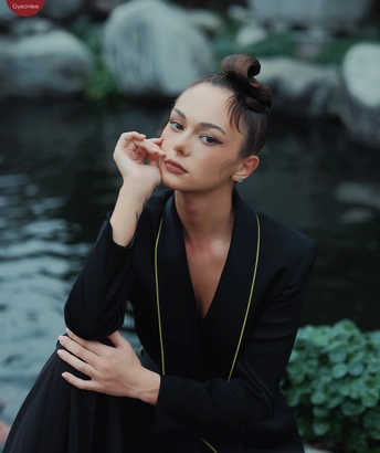 美丽的年轻女子穿着黑色连衣裙在池塘前摆姿势