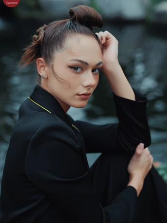 一位穿着全黑衣服的年轻女子在河边摆姿势