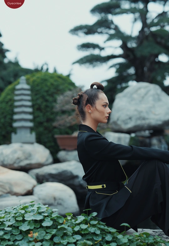 一个穿着黑色连衣裙的年轻女子坐在一些岩石上