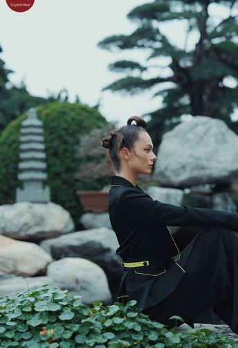 一个穿着黑色连衣裙的年轻女子坐在一些岩石上