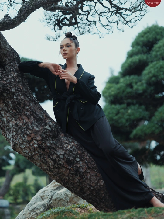 一位穿着全黑衣服的女人靠在一棵树上