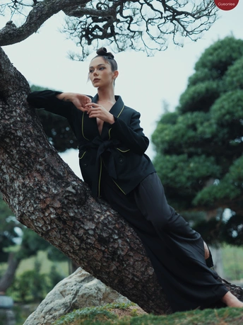 一位穿着全黑衣服的女人靠在一棵树上