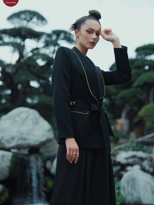 一位穿着黑色连衣裙的女士站在瀑布前