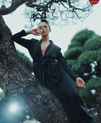 一位穿着全黑衣服的模特儿在树上摆姿势