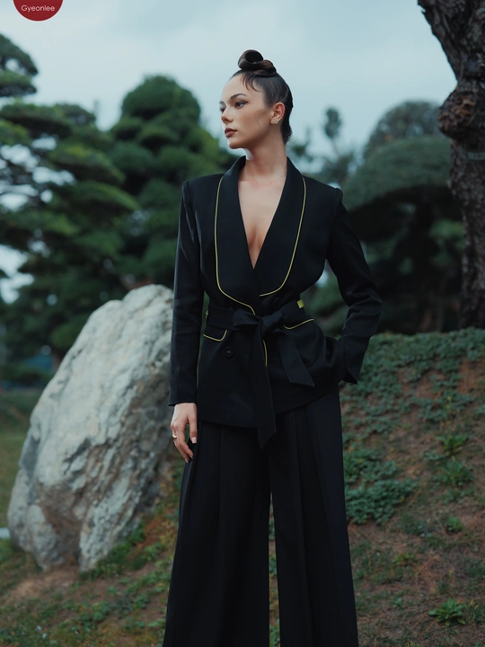 一个穿着黑色西装的模特站在岩石前