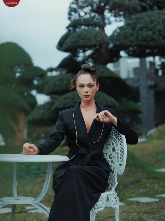 一位穿着黑色连衣裙的女人坐在白色长凳上