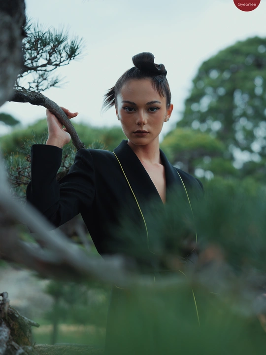 在森林中 一个穿黑色衣服的女孩在松树和树枝之间摆姿势