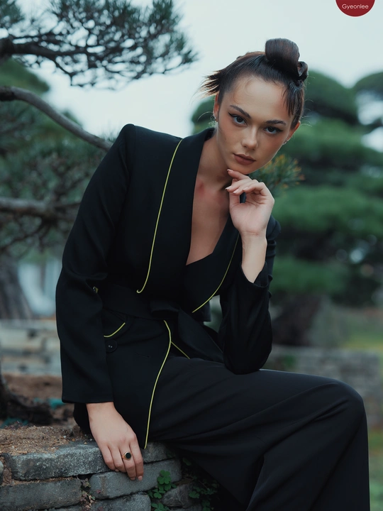 一位穿着黑色西装的女人坐在墙上