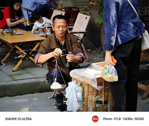一个老人坐在桌子旁用筷子吃饭。