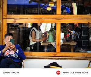 一位男士坐在餐厅里 正在查看他的手机并拍照。