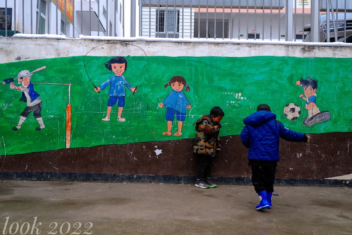 墙上画着年轻人在街上踢足球和棒球的壁画