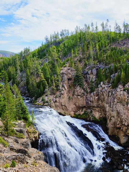 a waterfall in the mountains on a sunny day