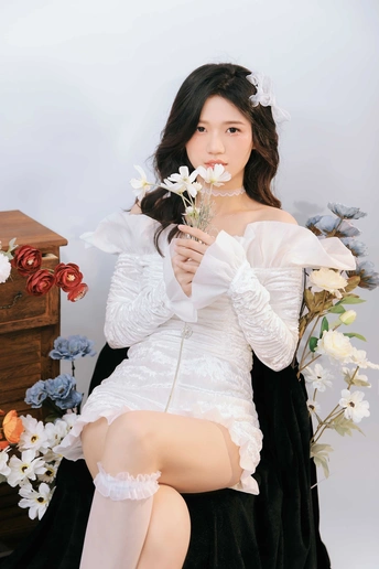 一位身穿白色连衣裙、肩上挎着白花的美丽年轻女子