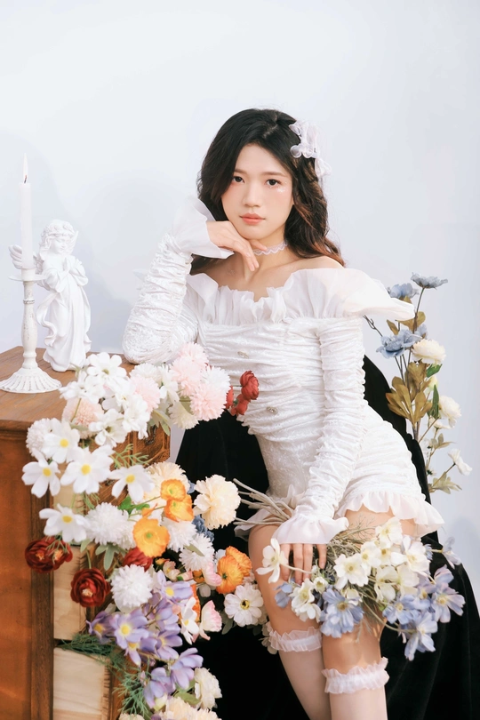 一个穿着白色连衣裙的年轻女子坐在花上