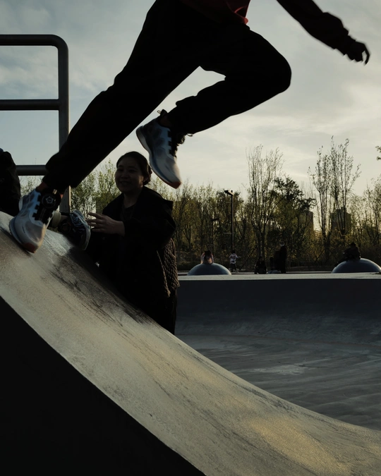 一个年轻人骑着滑板在滑板公园 人们观看。