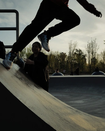 一个年轻人骑着滑板在滑板公园 人们观看。