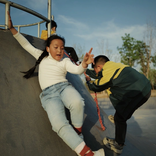 一个年轻男孩和一个女人在滑板公园的斜坡上滑板。