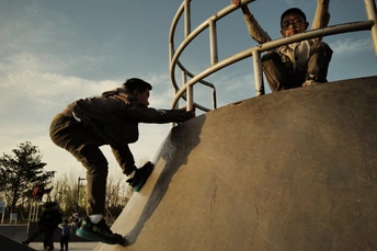 一个年轻人骑着滑板在滑板公园的坡道上滑行。